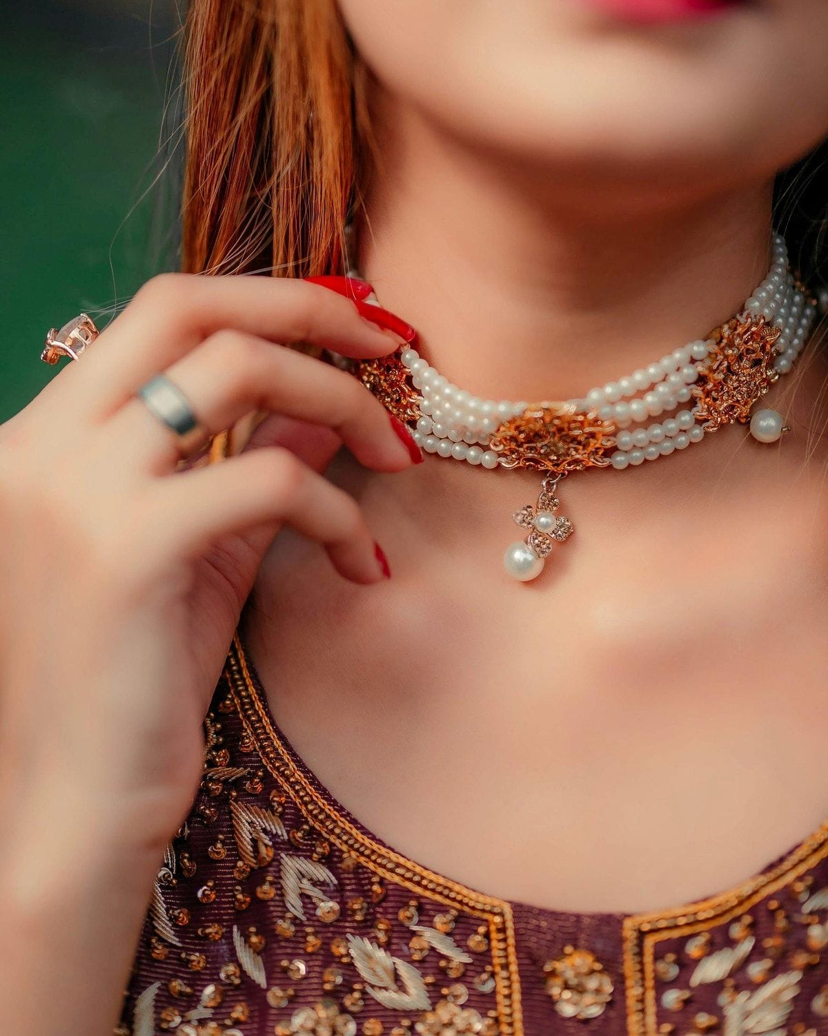 Close-up of pearl necklace and ring with intricate design