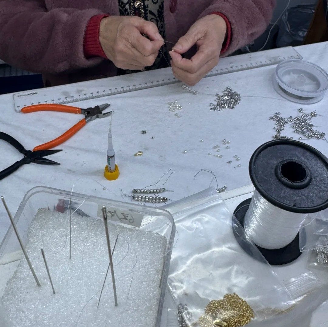Hands stringing and inspecting freshwater pearls at a workshop in Zhuji, China — a real look at the human craft behind genuine pearl jewelry.