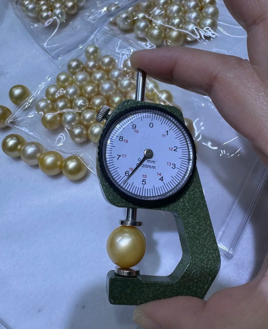 Pearl diameter gauge measuring a gold pearl at a Zhuji pearl market stall