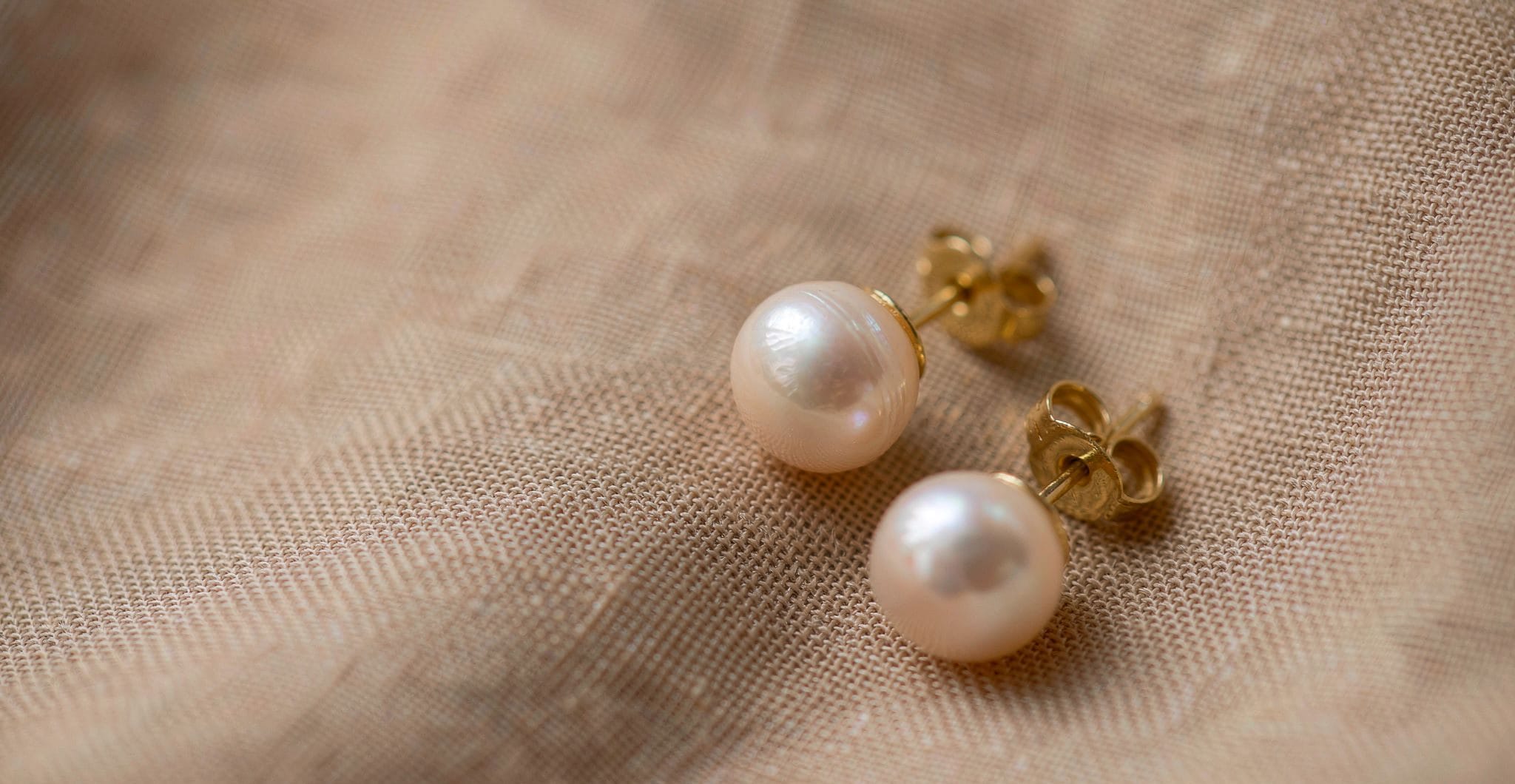 Classic white freshwater pearl stud earrings, round, on linen