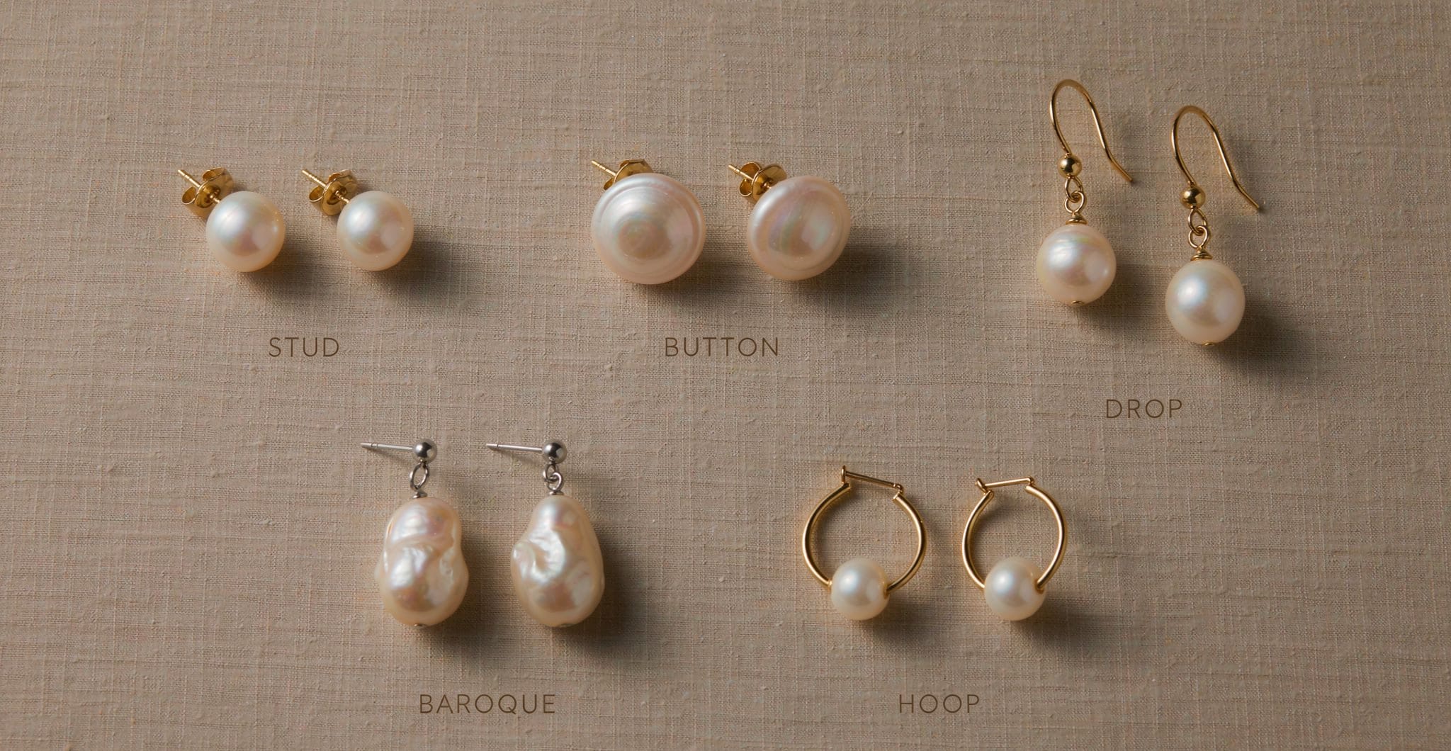 Five freshwater pearl earring styles laid flat on linen: stud, button, drop, baroque, and hoop