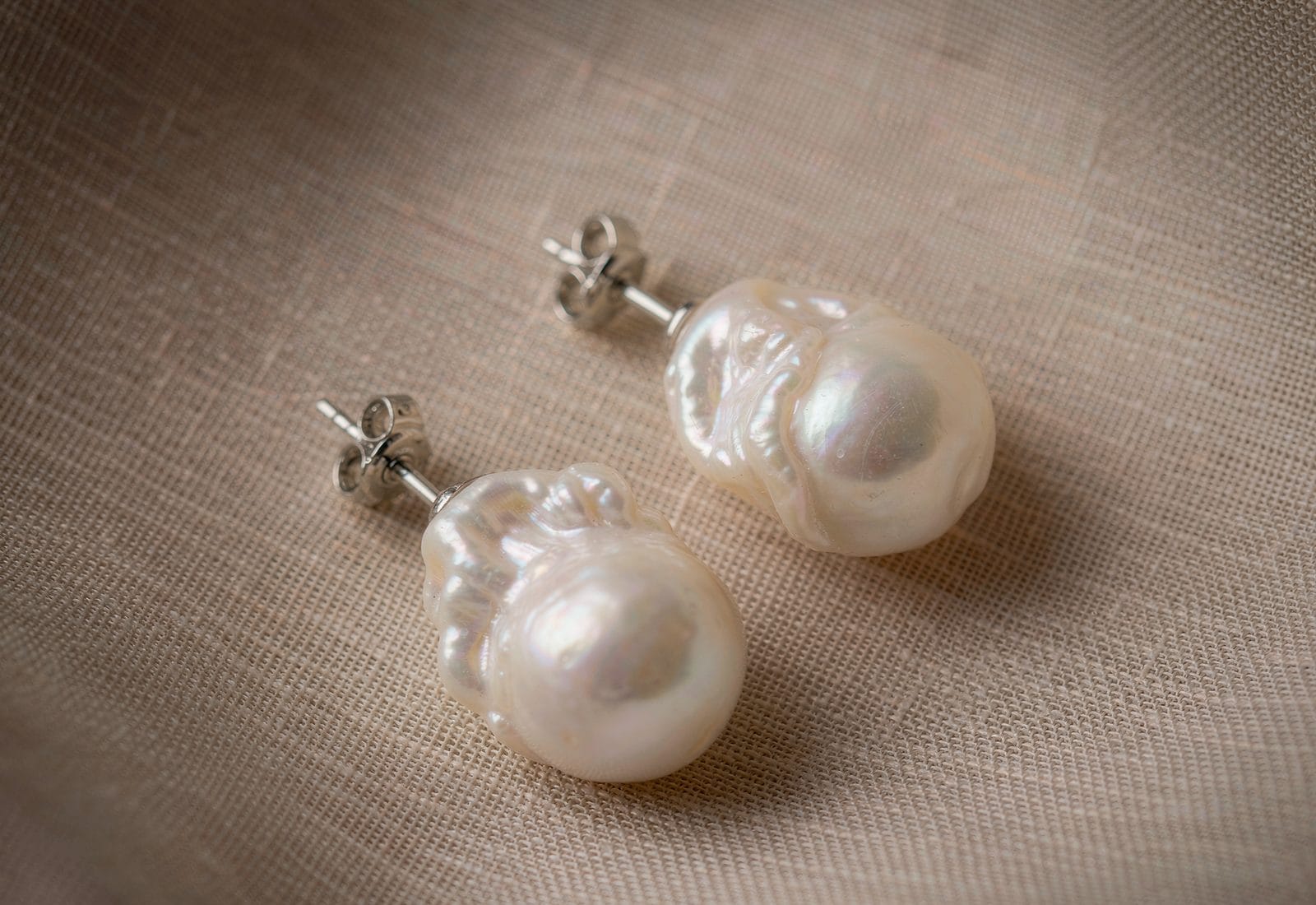 Freshwater pearl stud earrings showing luster variation - high-luster round pearls compared with softer coinch pearls