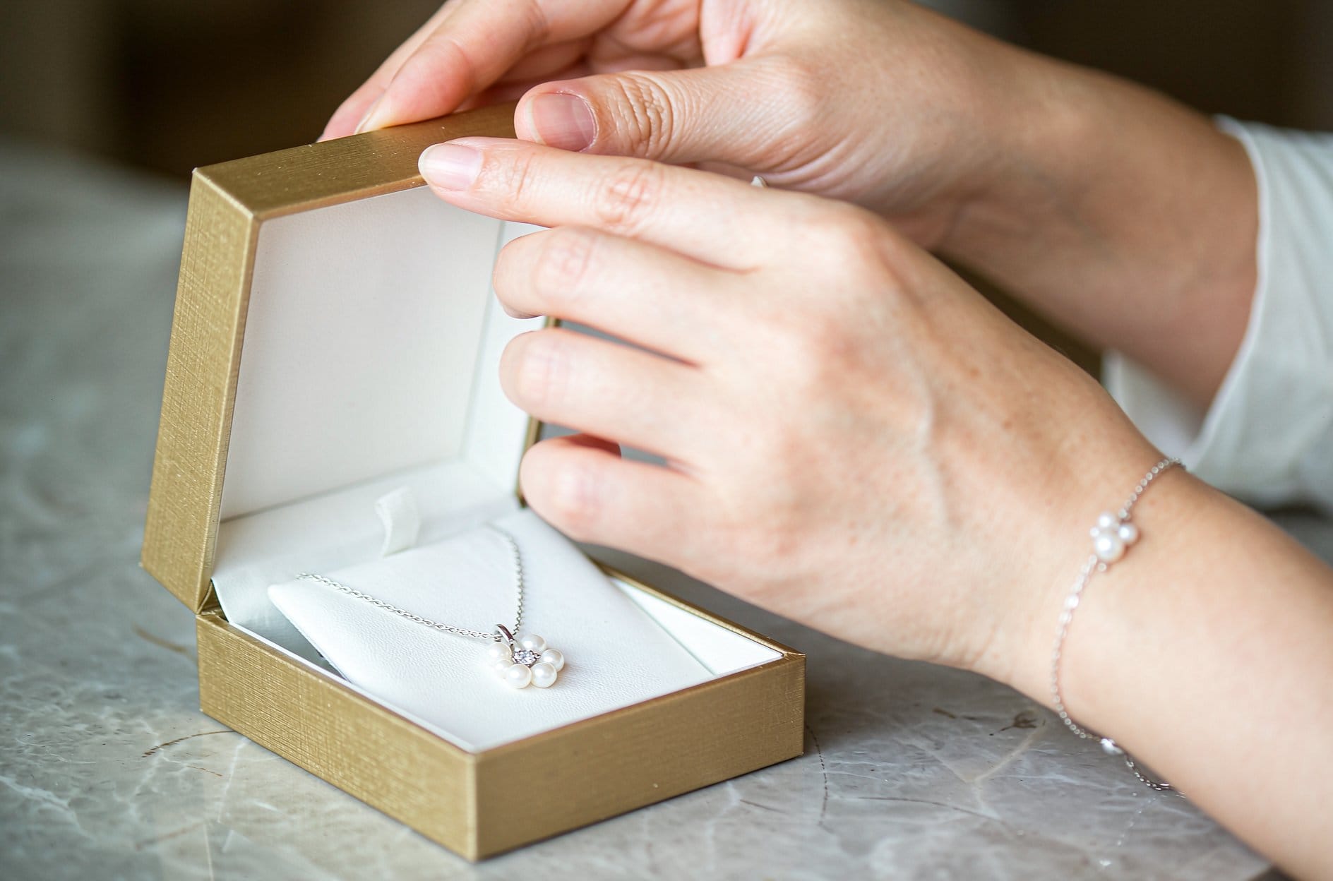 Woman browsing pearl necklaces at a jewelry display to find the right pearl gift for her girlfriend