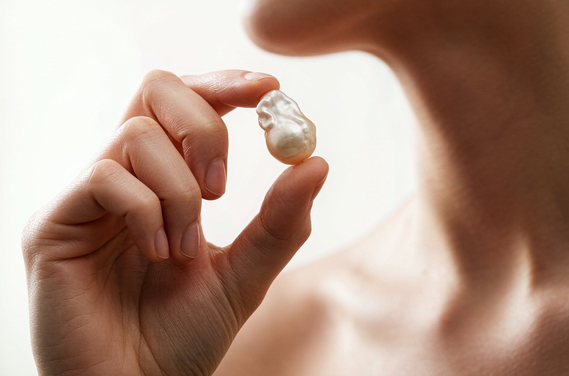 Hands opening a gold gift box with a pearl pendant necklace for a pearl gift for girlfriend