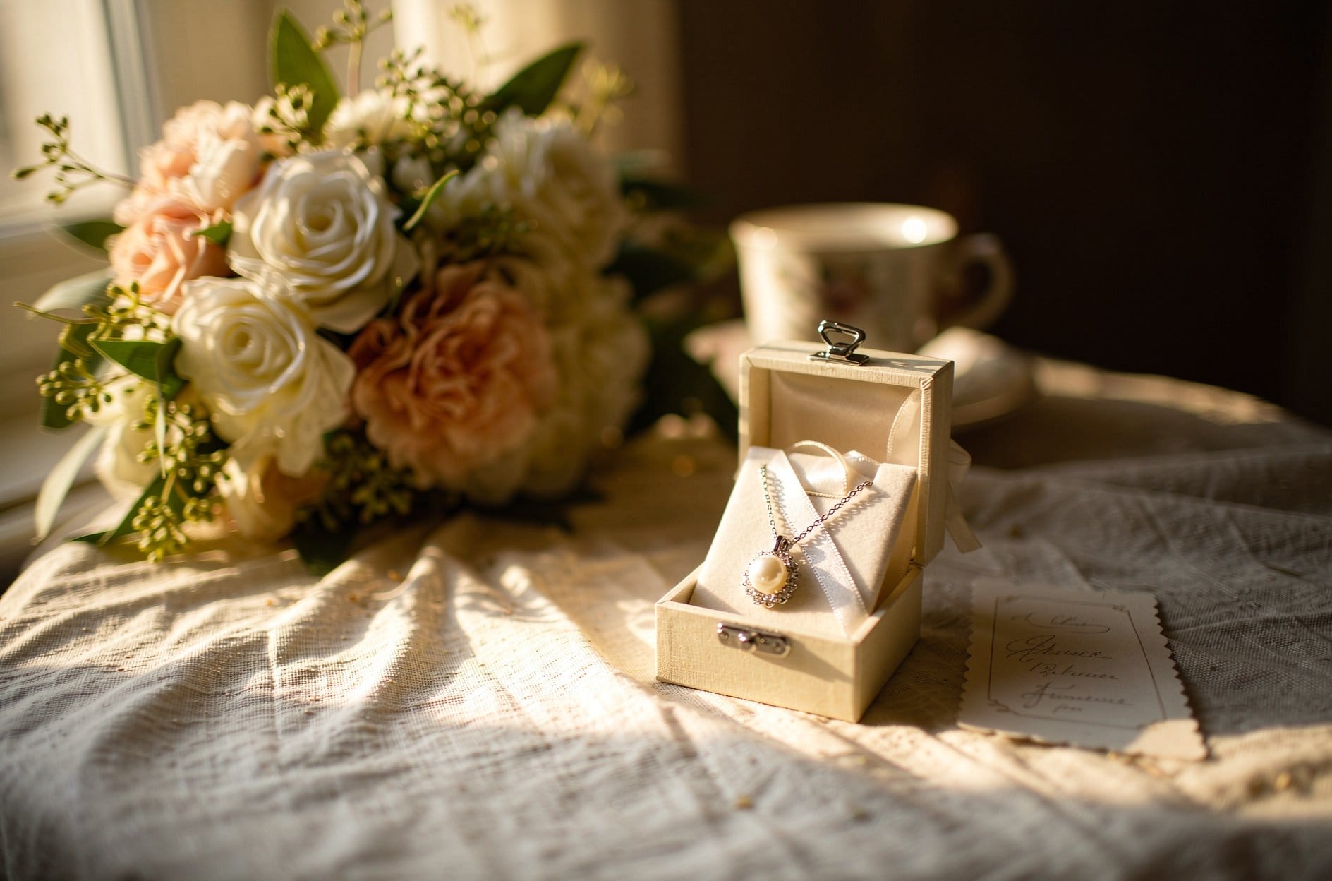 Pearl pendant necklace displayed in an open gift box beside fresh flowers for pearl vs moissanite