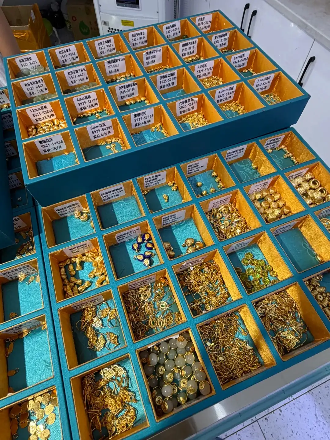 Gold-plated clasps and findings at a Zhuji market stall, illustrating affordable hardware options for freshwater pearl necklaces.